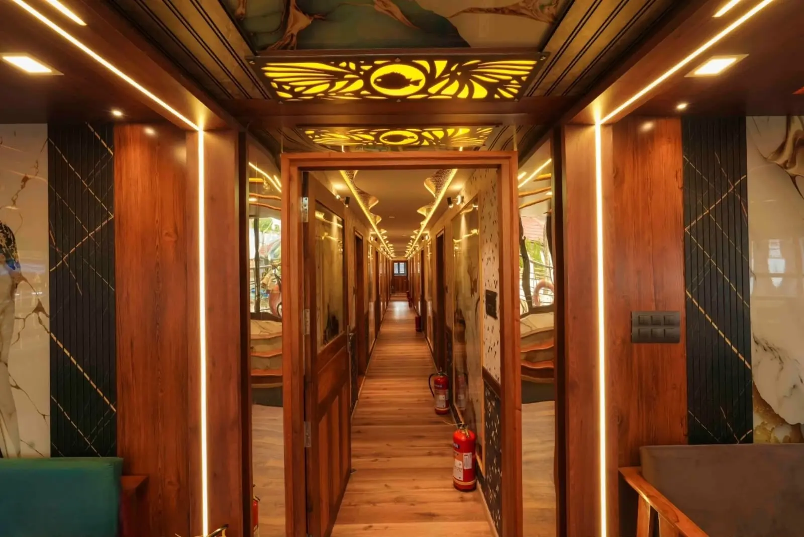 Corridor of bedrooms with lit fish-motif panels on a luxury houseboat